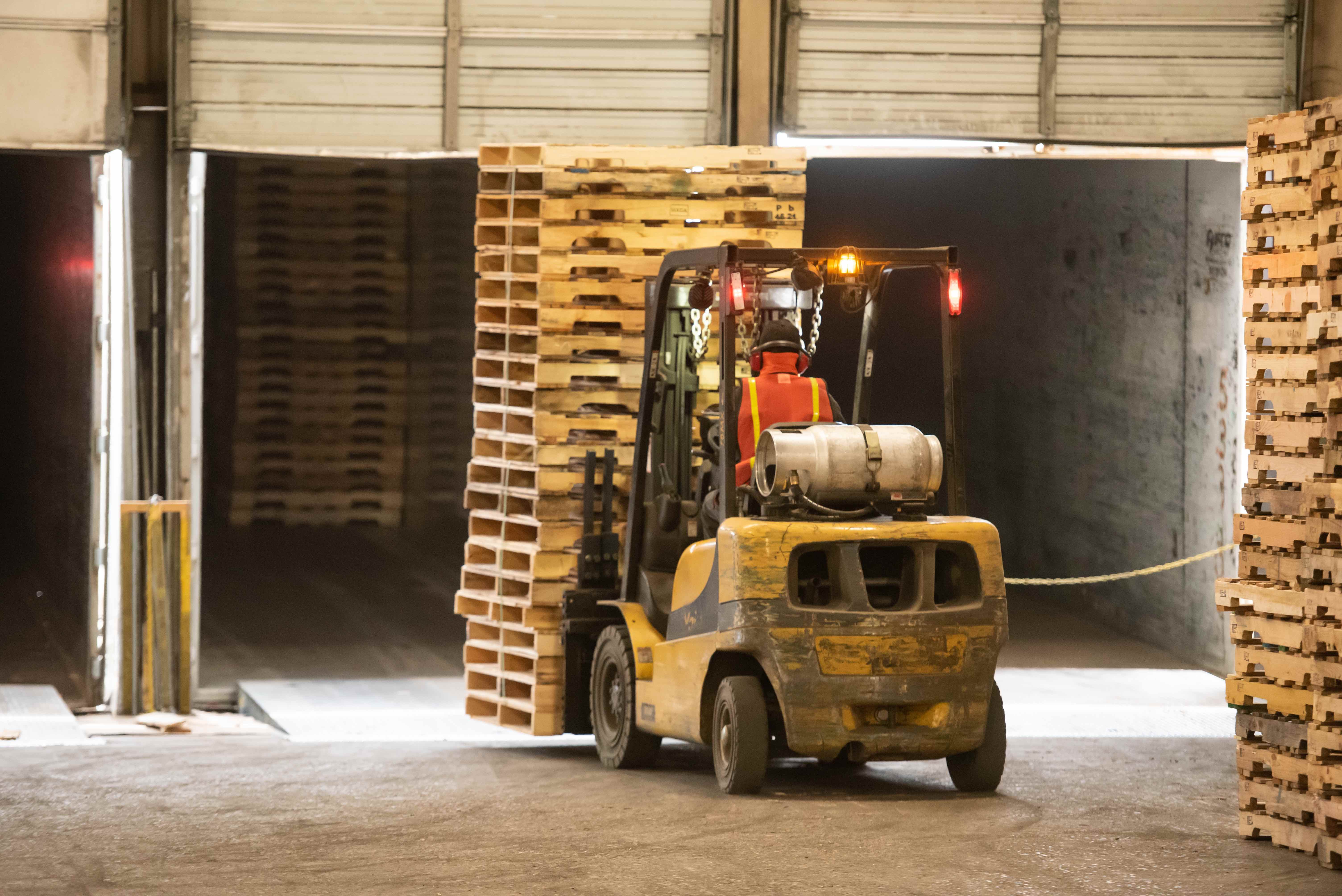 Forklift moving recycled pallets in a distribution center